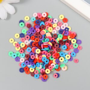 Россыпь мелких плоских круглых бусин. Они разноцветные — есть розовые, фиолетовые, синие, красные, белые, оранжевые и другие оттенки. У каждой бусины в центре есть отверстие. Фон — светло-серый.